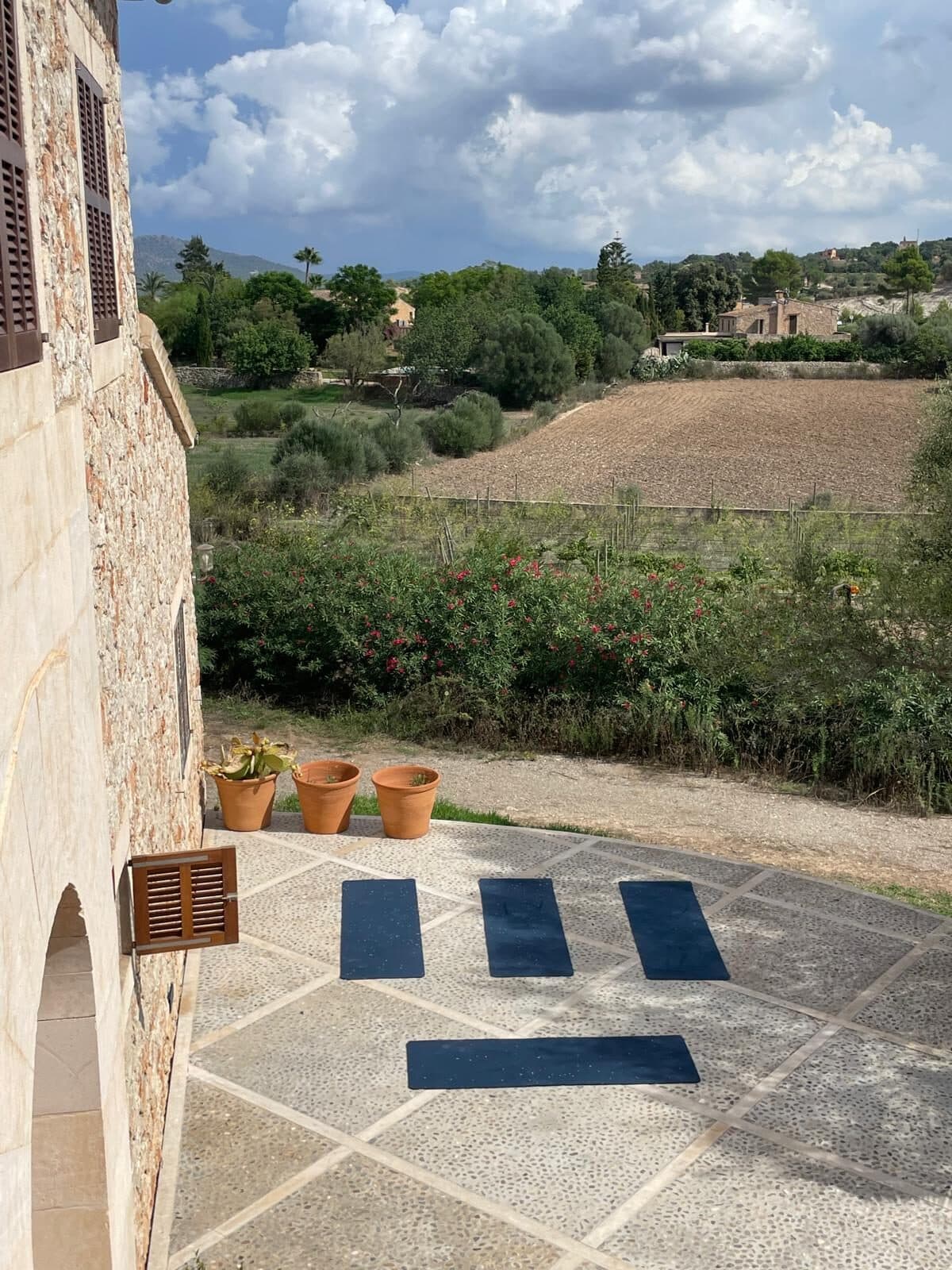 Four yoga mats on a finca terrace in Mallorca, fields and trees in the background
