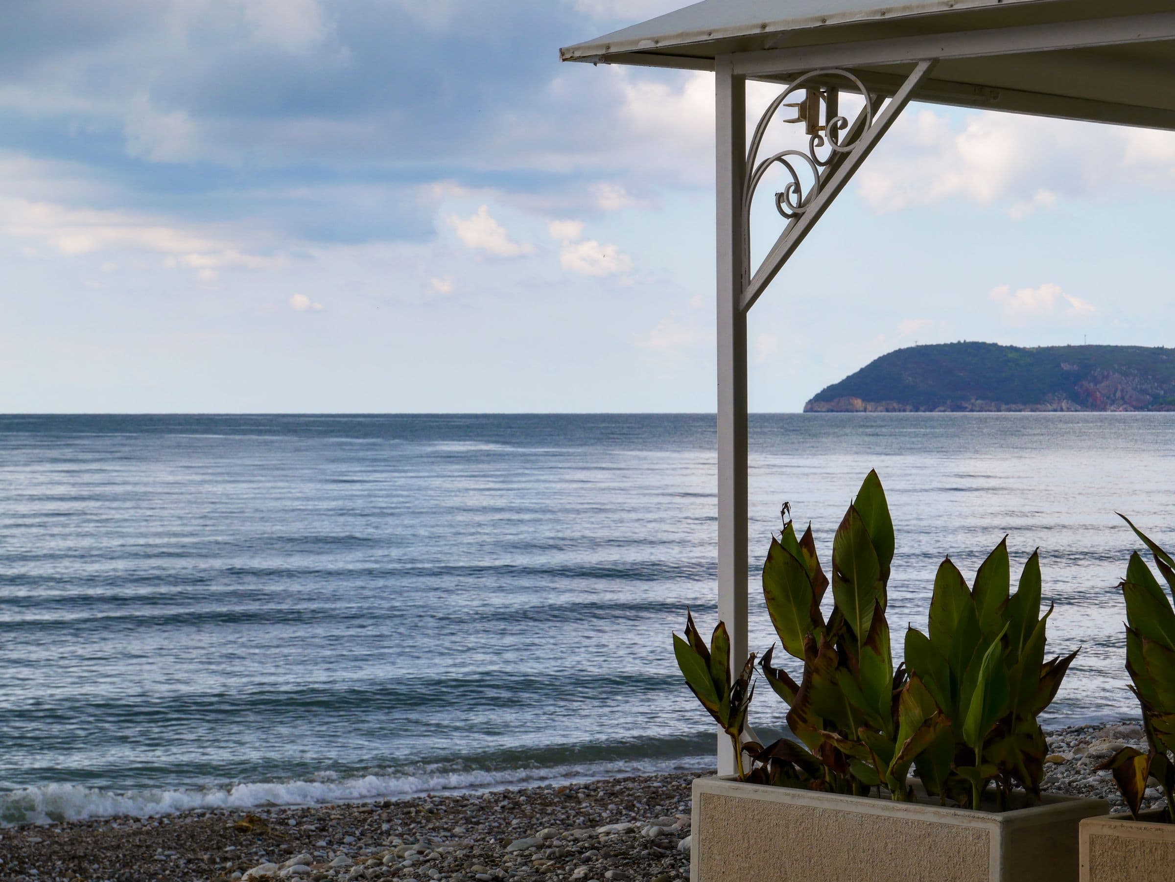 Terrasse mit Pflanzen und Blick aufs Meer und eine Insel