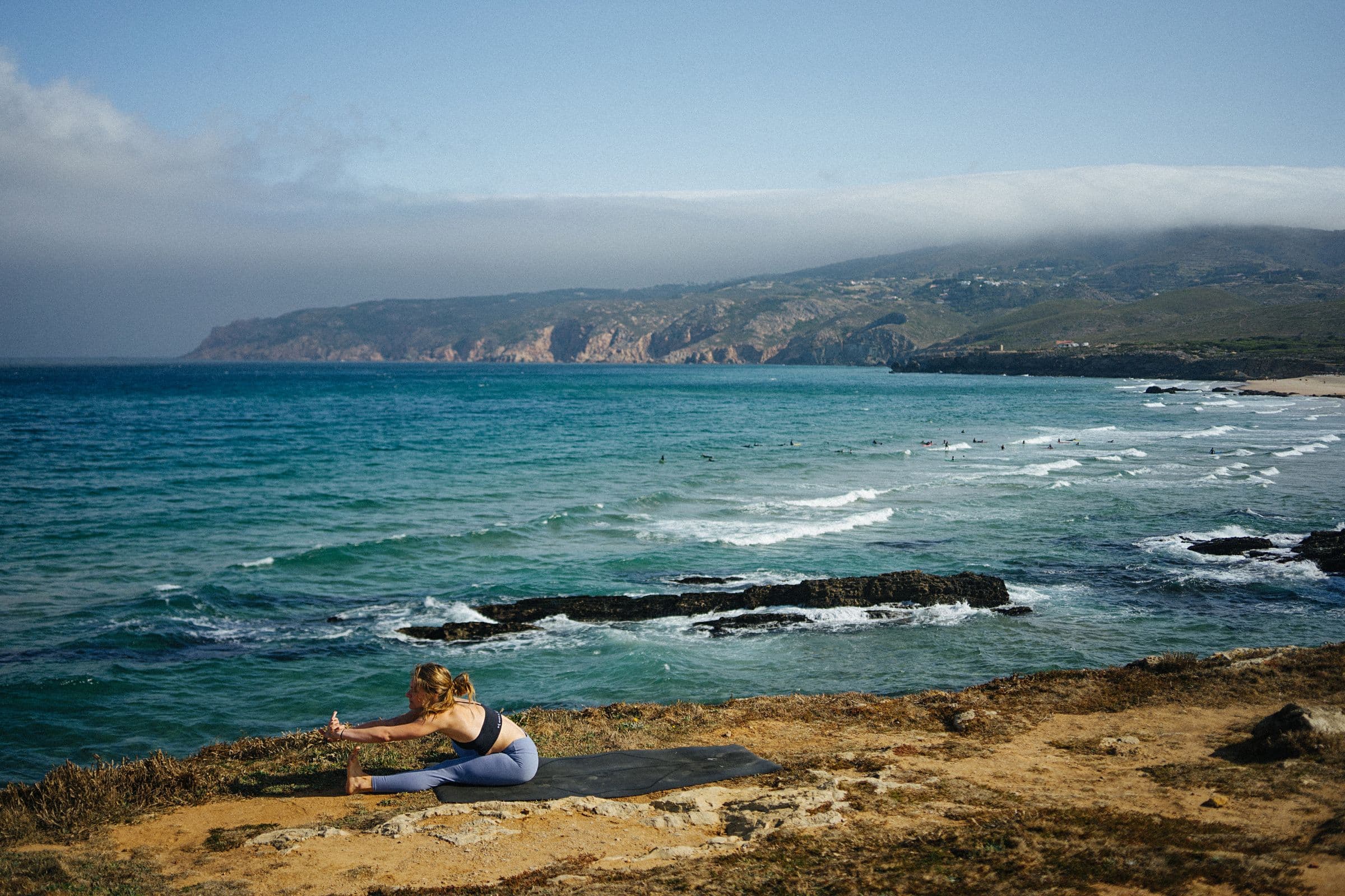 Yoga auf einer Matte an einer weiten Felsküste am Meer